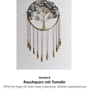 May include: A gold-toned metal dreamcatcher with a circular frame and a tree of life design. The tree is adorned with clear and gray crystals. The dreamcatcher has multiple strands of beads and feathers hanging from the bottom.