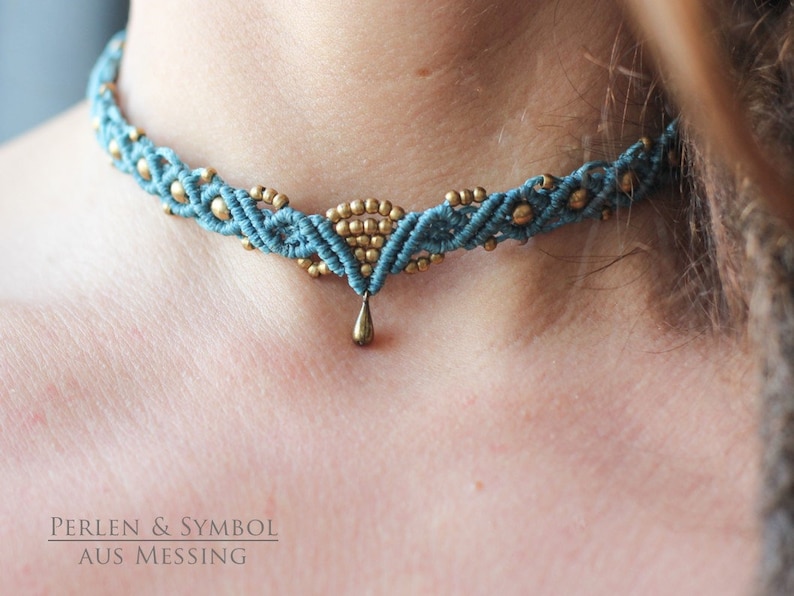 May include: A teal blue and gold macrame choker necklace with a small teardrop pendant. The necklace is made with a knotting technique and features small gold beads.