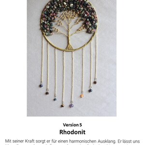 May include: A gold wire tree of life with pink, green, and black stones. The tree is hanging from a gold chain with smaller stones hanging from the branches. The text "Version 5 Rhodonit" is below the image.