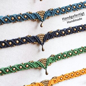 May include: Four handmade macrame bracelets with gold beads and a dangling charm. The bracelets are in shades of blue, green, and yellow. The text "Handgefertigt Handmade" is visible in the image.