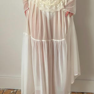 May include: A white vintage dress with a lace bodice and sheer skirt. The dress features long sleeves and a tiered skirt design. The bodice is adorned with intricate lace detailing, and the skirt has a flowing, ethereal quality. The dress is suitable for special occasions.