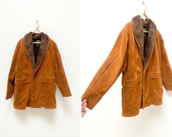 Könnte beinhalten: Eine braune Wildlederjacke mit einem Kunstfellkragen. Die Jacke hat einen Knopfverschluss und zwei Taschen.