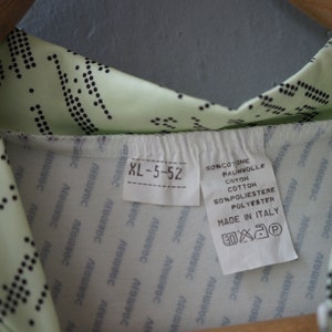 May include: A light green shirt with a black polka dot pattern. The shirt has a white tag with the text "XL-5-52", "SONCOTONE", "RAUNWOLLE", "COTTON", "SONPOLIESTERE", "POLYESTER", "MADE IN ITALY", and washing instructions.
