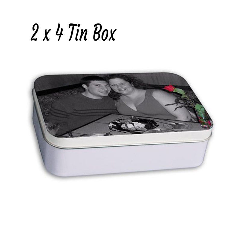 May include: A white rectangular tin box with a black and white photo of a couple on the lid. The photo shows a man and a woman smiling at the camera. There is a red rose in the background.