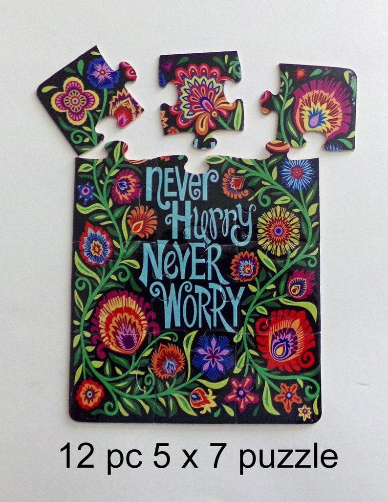 May include: A 12-piece jigsaw puzzle with a floral design and the words "Never Hurry Never Worry" on a black background. The puzzle pieces are arranged in a rectangle shape.