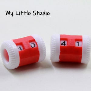 Könnte beinhalten: Zwei rot-weiße mechanische Zähler mit den Zahlen 10 und 41. Die Zähler haben eine zylindrische Form mit einem roten Mittelteil und weißen Enden. Der Text "My Little Studio" ist im Hintergrund zu sehen.