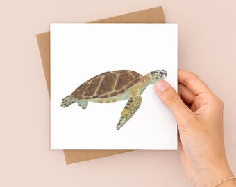 May include: A square greeting card featuring a detailed watercolor illustration of a sea turtle with a brown patterned shell and light green skin, shown swimming against a plain white background, paired with a brown kraft paper envelope.