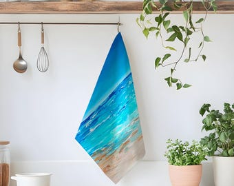 May include: A rectangular kitchen towel featuring a vibrant abstract painting of a tropical beach scene. The design displays deep blue ocean water transitioning into bright turquoise waves that wash onto a sandy beige shore with textured brushstrokes.