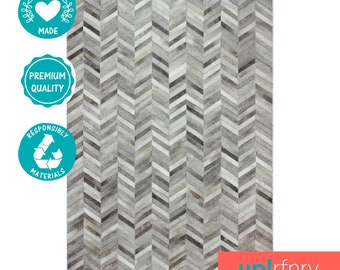 May include: A gray and white chevron patterned rug made from ethically sourced materials. The rug is made with high-quality materials and is responsibly sourced. The rug is perfect for adding a touch of style to any room.
