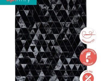 May include: Black and white geometric patterned rug made from leather. The rug is handcrafted and has a reduced carbon footprint. The rug is available at low-end prices.