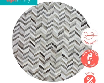 May include: A round, gray and white chevron patterned rug made from cowhide. The rug is handcrafted and has a reduced carbon footprint. The rug is available at low-end prices.