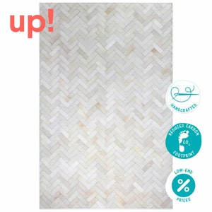 May include: White leather rug with a herringbone pattern. The rug is handcrafted and has a reduced carbon footprint. The rug is also low-end priced.