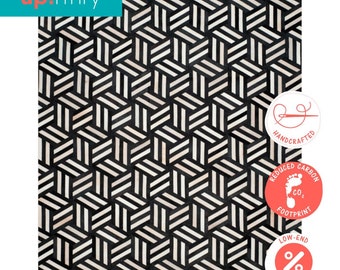May include: Black and white geometric patterned rug made from cowhide. The rug is handcrafted and has a reduced carbon footprint. The rug is available at low-end prices.