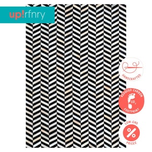 May include: Black and white chevron patterned rug with a handmade, reduced carbon footprint, and low-end prices label.