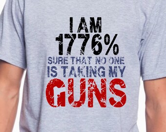 May include: A gray t-shirt with a distressed graphic print that reads "I am 1776% sure that no one is taking my GUNS".