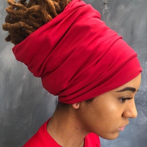 Peut inclure: Vue de profil d'une personne portant un foulard rouge vif. Le foulard est fait d'un tissu doux et drapé, couvrant le haut de la tête et les cheveux. La personne porte également un haut rouge.