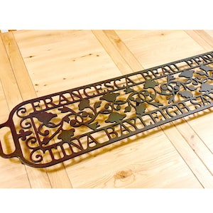 May include: A black metal decorative doormat with the names "Francesca Beau Penny", "Tina Bayleigh", and "Savannah" in a decorative font.