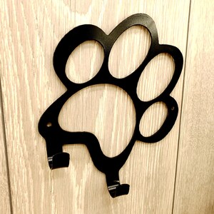 May include: Black metal paw print shaped wall hook with two hooks.