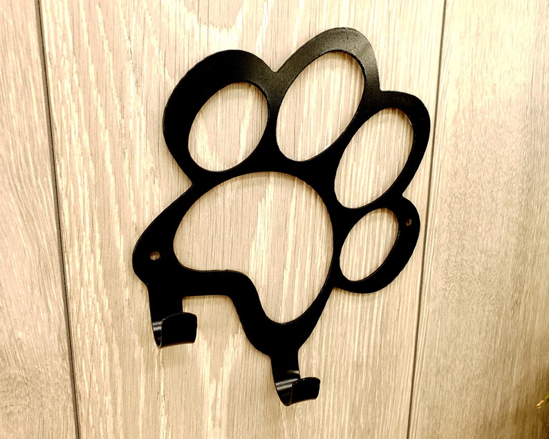May include: Black metal paw print shaped wall hook with two hooks.