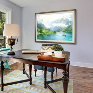 May include: A framed watercolor painting of a mountain lake scene with boats and trees. The painting is hanging on a wall above a dark wood desk with a lamp and a plant.