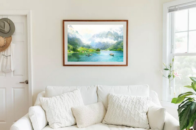 May include: A framed watercolor painting of a lake surrounded by mountains. The lake is a bright blue and the mountains are green and white. There are small boats on the lake.