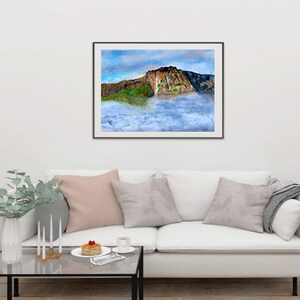 May include: A framed photograph of a large rock formation with a waterfall cascading down the side. The rock is surrounded by clouds and a blue sky.