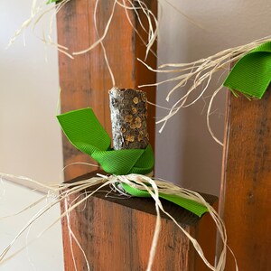 May include: Three wooden pumpkins decorated with green ribbon and natural twine. The pumpkins are stacked on top of each other.