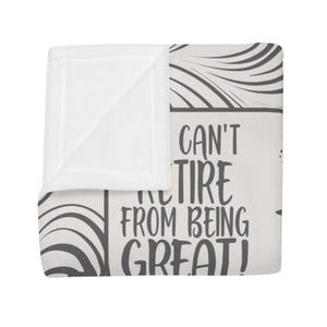 May include: A white blanket with the text "Can't Tire From Being Great!" in black. The blanket has a folded corner, and the design includes gray curved lines.