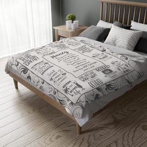 May include: A white blanket with a black floral design and text. The text includes the name "Nancy" and phrases like "Retirement only means time for an adventure" and "Rocking the retired life."
