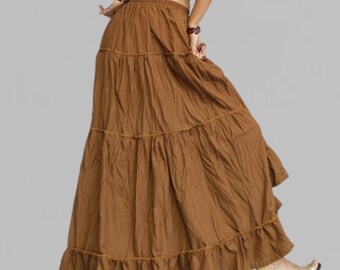 May include: A long, tiered brown skirt with a flowing, bohemian style. The skirt features multiple layers of fabric, creating a full, flared silhouette. The skirt is made of a soft, lightweight material, perfect for warm weather. The skirt has a ruffled hem.