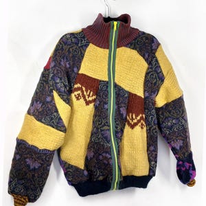 May include: A vintage-style zip-up jacket with a patchwork design. The jacket features a high collar, a neon green zipper, and a mix of colors including yellow, burgundy, navy, and brown. The sleeves and body have different patterned sections.