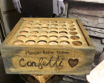 May include: A wooden box with a sign that says "Please take some confetti" and a heart. The box has many holes in the top, likely for holding confetti.