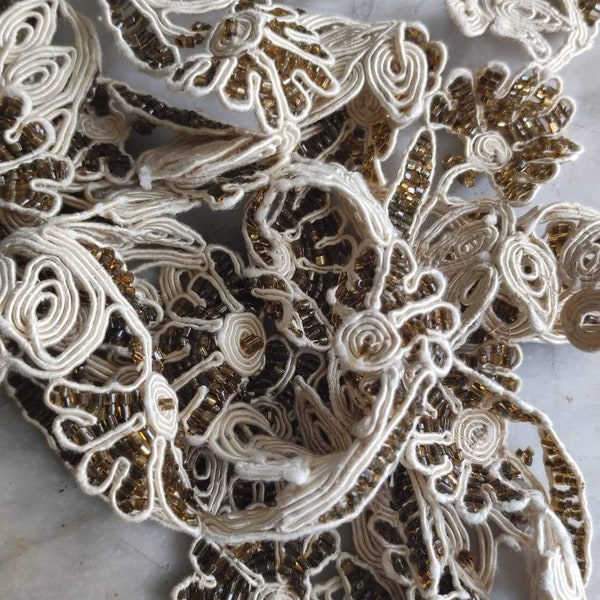 Crema di perlati edoardiani e finiture in soutache di seta dorata.