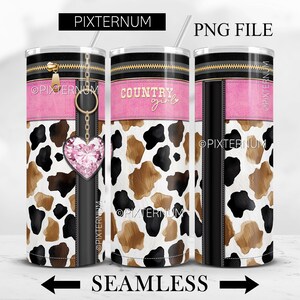 May include: A white tumbler with a brown and black cow print design. The tumbler has a pink band with the text "COUNTRY girl" and a black zipper detail. A gold chain with a pink rhinestone heart hangs from the top of the tumbler.