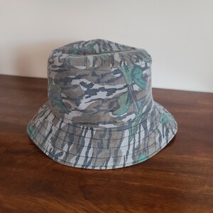 May include: A camouflage bucket hat with a green, brown and white pattern.