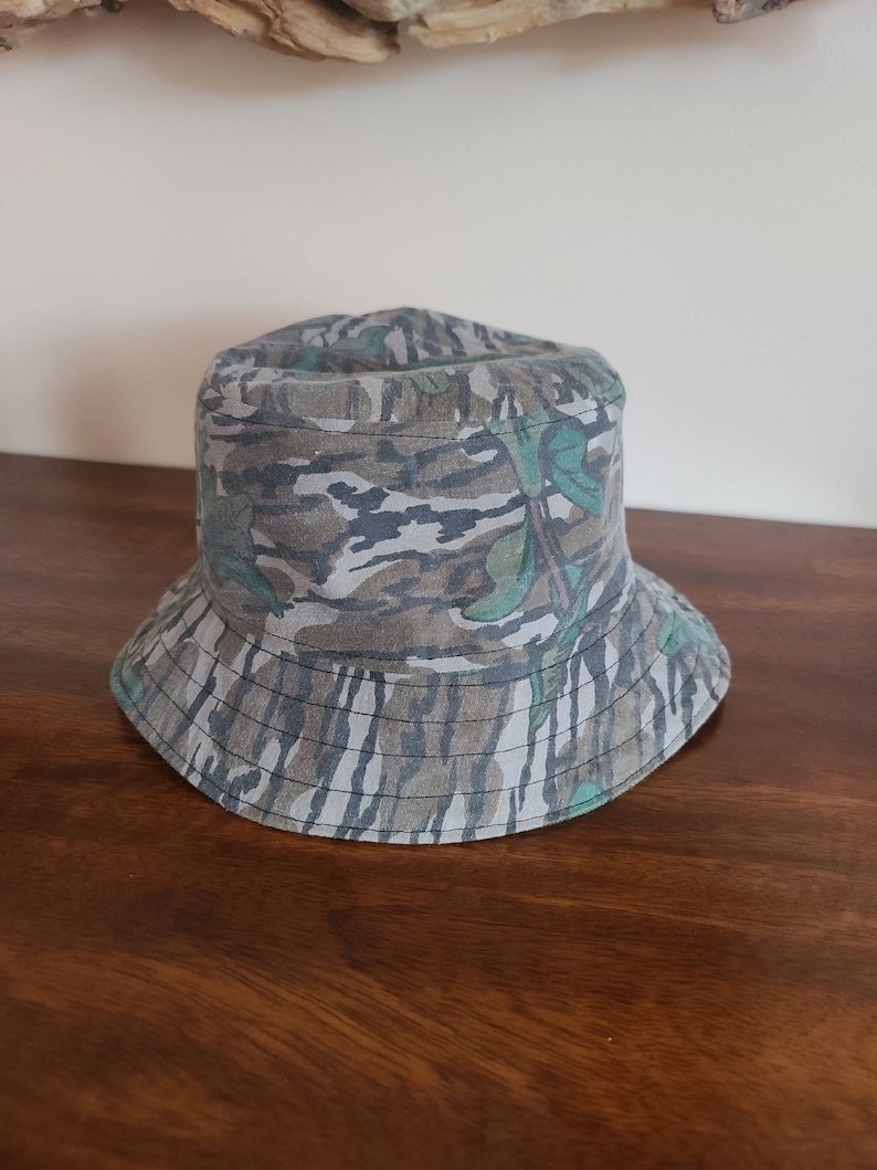 May include: A camouflage bucket hat with a green, brown and white pattern.