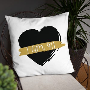 Puede incluir: Almohada blanca con un corazón negro y una cinta dorada que dice "Soy 911".