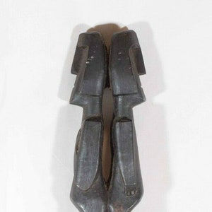 May include: A dark wood carving of two figures standing on top of an elephant. The figures are carved in a stylized manner, with simple features and rounded bodies. The carving is a traditional African art piece.