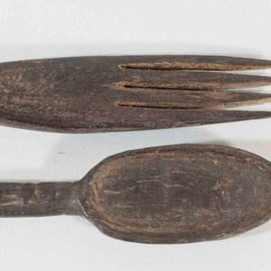 May include: A set of two wooden utensils, a spoon and a fork, both with a dark brown finish. The spoon has a rounded bowl and the fork has four tines.