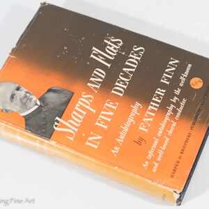 May include: A vintage book titled "Sharps and Flats in Five Decades" by Father Finn. The cover features a portrait of a man and text in white and orange against a dark brown background. The book is an autobiography.