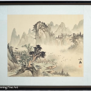 Puede incluir: Una pintura tradicional japonesa de tinta y acuarela que representa un paisaje montañoso brumoso con un pequeño pueblo en primer plano. La pintura está enmarcada en negro y presenta un sello rojo con un solo carácter chino.