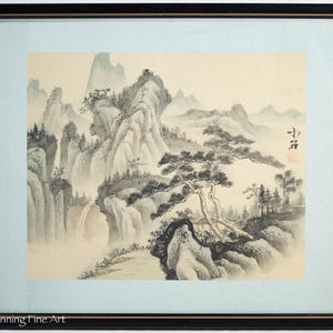 Puede incluir: Una pintura de tinta negra y blanca de un paisaje montañoso con un pino en primer plano. La pintura está enmarcada en un marco negro y tiene un passe-partout azul claro.