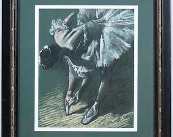 May include: A framed pastel drawing of a ballerina in a tutu, bending forward. The artwork features soft pastel colors, with the ballerina's tutu in shades of white and blue. The frame is black with gold accents.