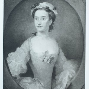 May include: A black and white portrait of a woman wearing a white lace cap and a white dress with a floral embellishment. The woman has a serious expression and is looking to the left.