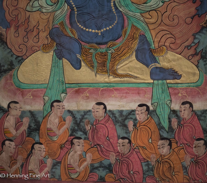 May include: A colorful painting depicting a deity surrounded by figures in prayer. The deity is blue with a gold crown and sits on a throne. The figures are dressed in red, orange, and yellow robes and have their hands clasped in prayer.
