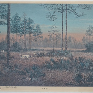 May include: A landscape print depicting a field with tall trees and two dogs. The artwork features a color palette of blues, greens, and browns, with a soft, hazy atmosphere. The dogs are white with brown spots. The print is framed.