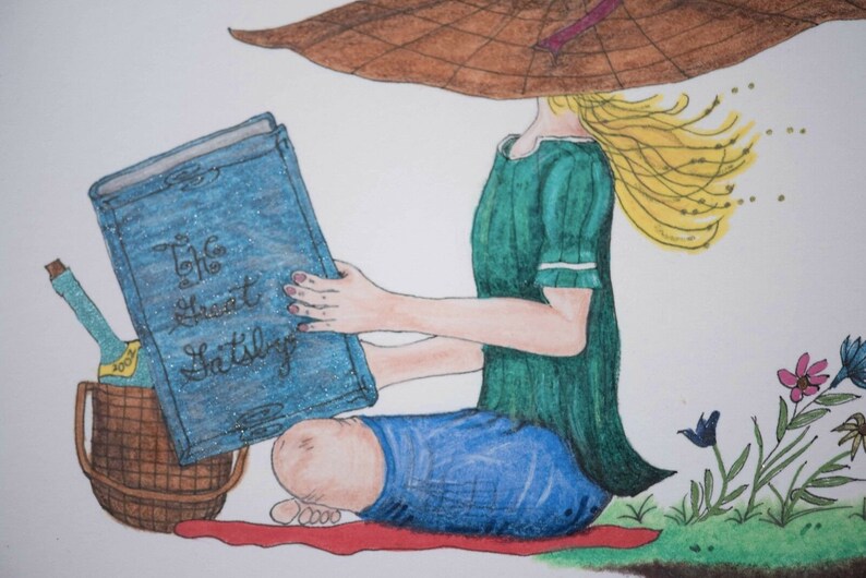 Puede incluir: Una mujer con un vestido verde y un sombrero marr&oacute;n se sienta en una manta roja y lee un libro azul titulado "The Great Gatsby".