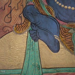 May include: A close-up of a colorful painting depicting a deity with a blue foot and a gold background. The deity is wearing a blue robe with a gold trim and a green sash. The painting is on a canvas and has a textured surface.