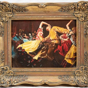 May include: A framed painting depicting a lively dance scene with multiple figures in colorful clothing. The painting is set in a dimly lit room with a dark background. The figures are in motion, with their arms and legs outstretched. The painting is framed in a gold-colored frame with ornate details.