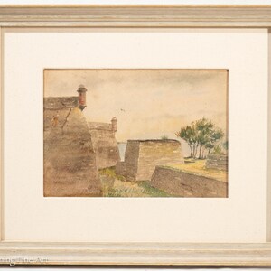 May include: Watercolor painting of a fortress with a light-colored frame. The artwork depicts stone walls, a small tower, and a few trees under a cloudy sky. The painting has a vintage aesthetic.